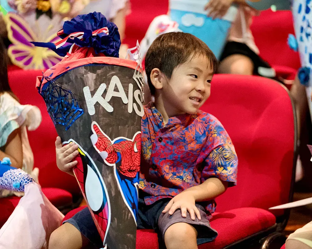 A young boy is holding a cone with the name kais on it.