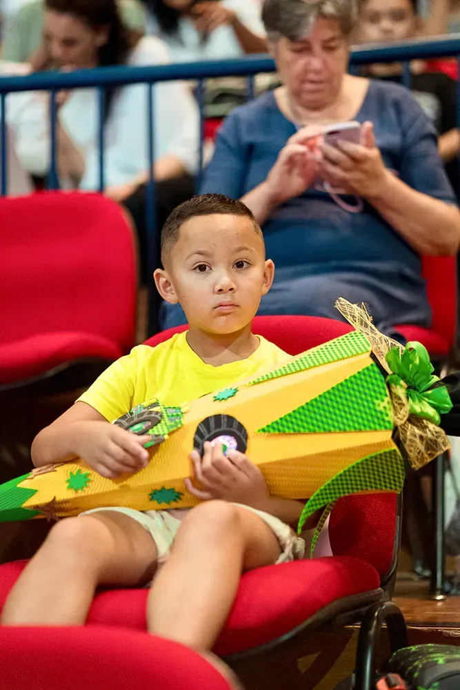 A young boy is sitting in a chair holding a cone.