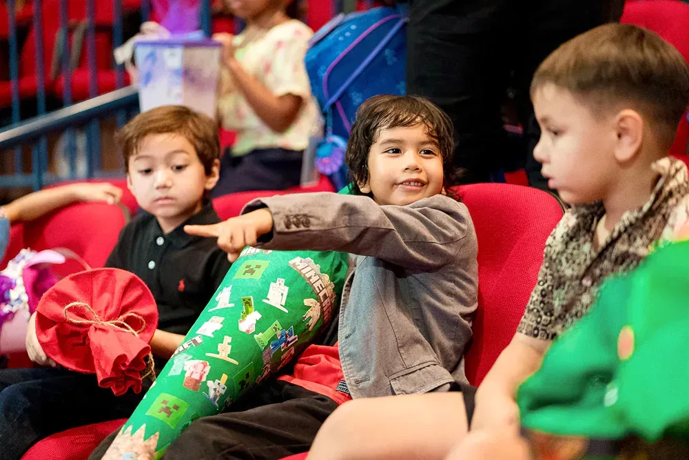 A group of children are sitting on a red couch.