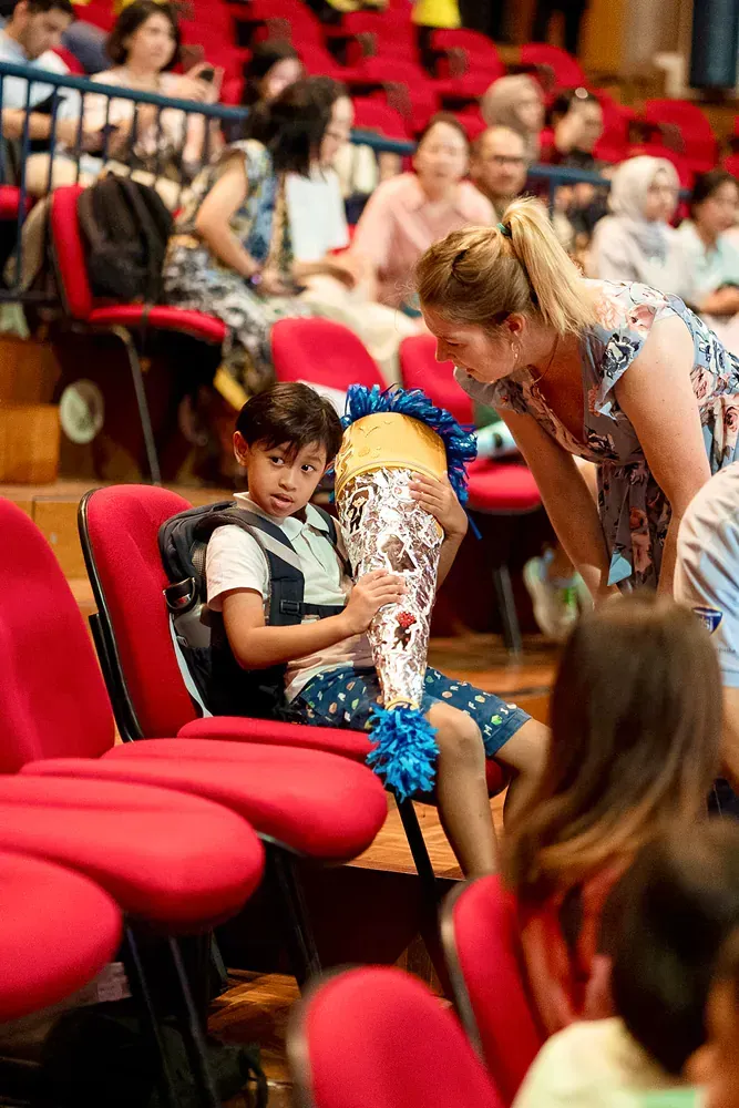 A woman is talking to a young boy in an auditorium.