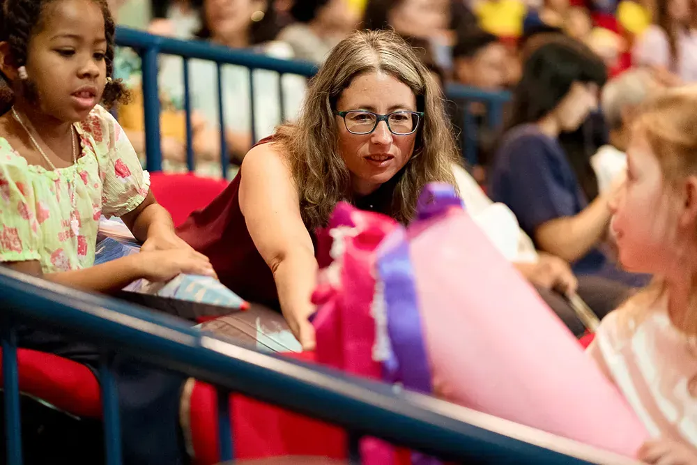 A woman is talking to two little girls while sitting in a stadium.