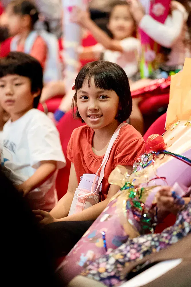A little girl is sitting in a crowd of children.