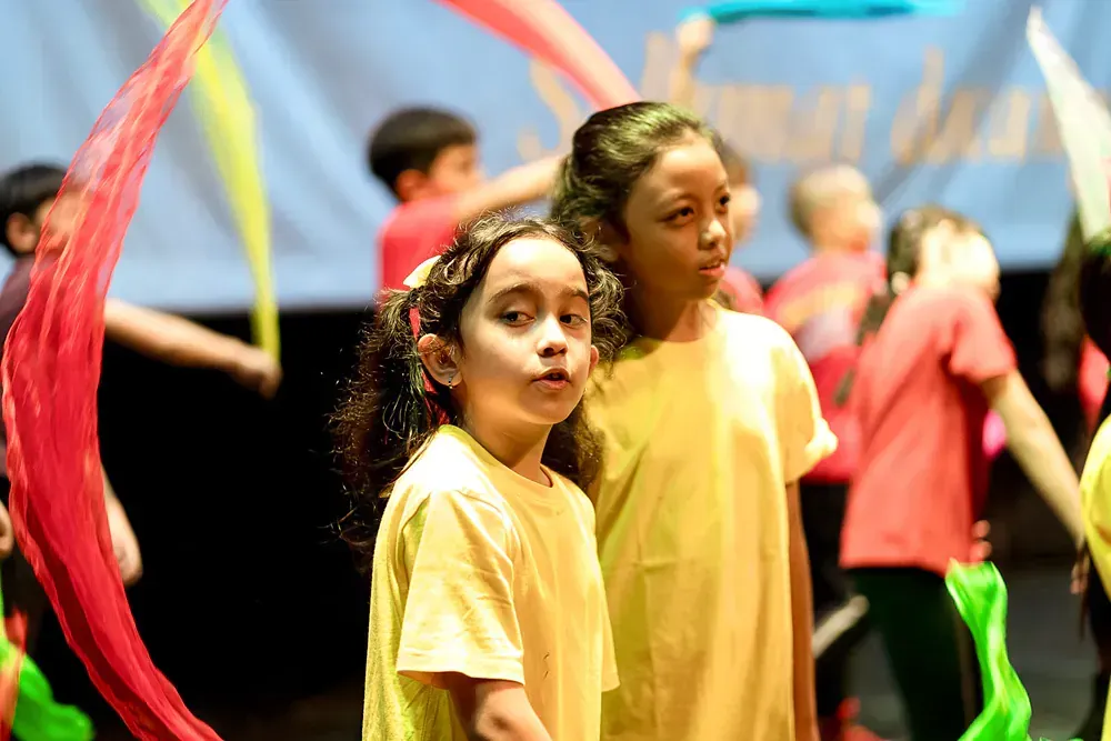 Two young girls are standing next to each other on a stage.