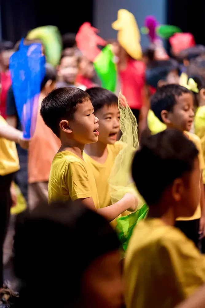 A group of children in yellow shirts are standing in a crowd.