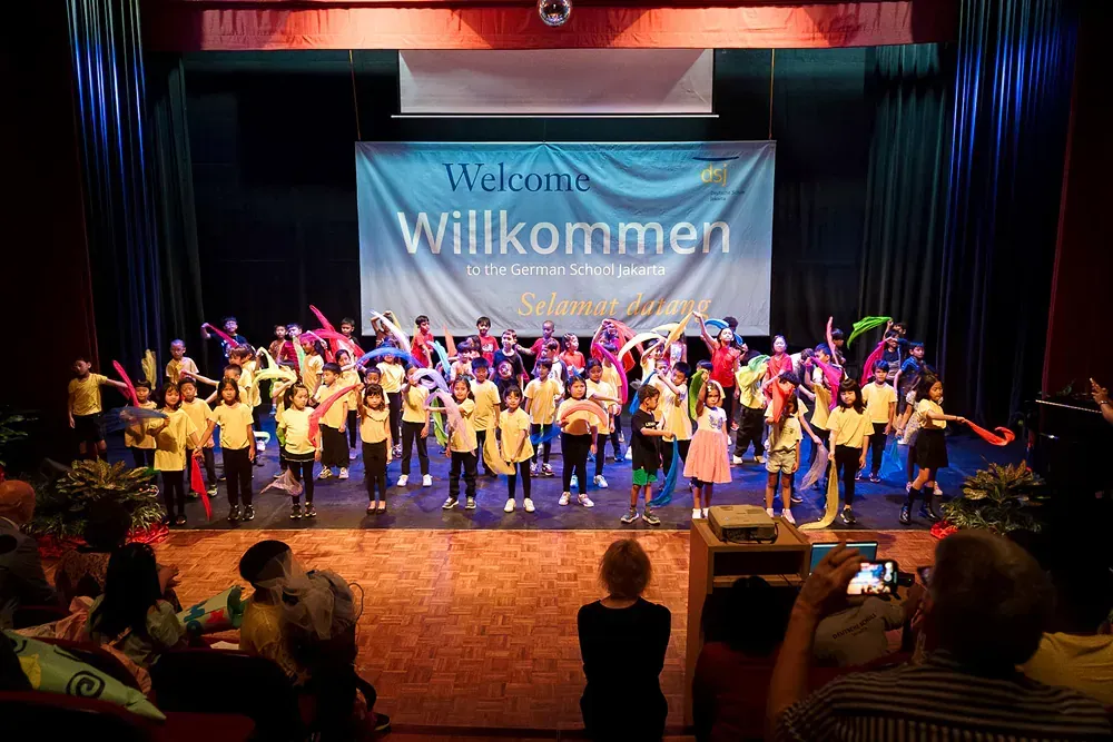 A group of children are dancing on a stage in front of a crowd.