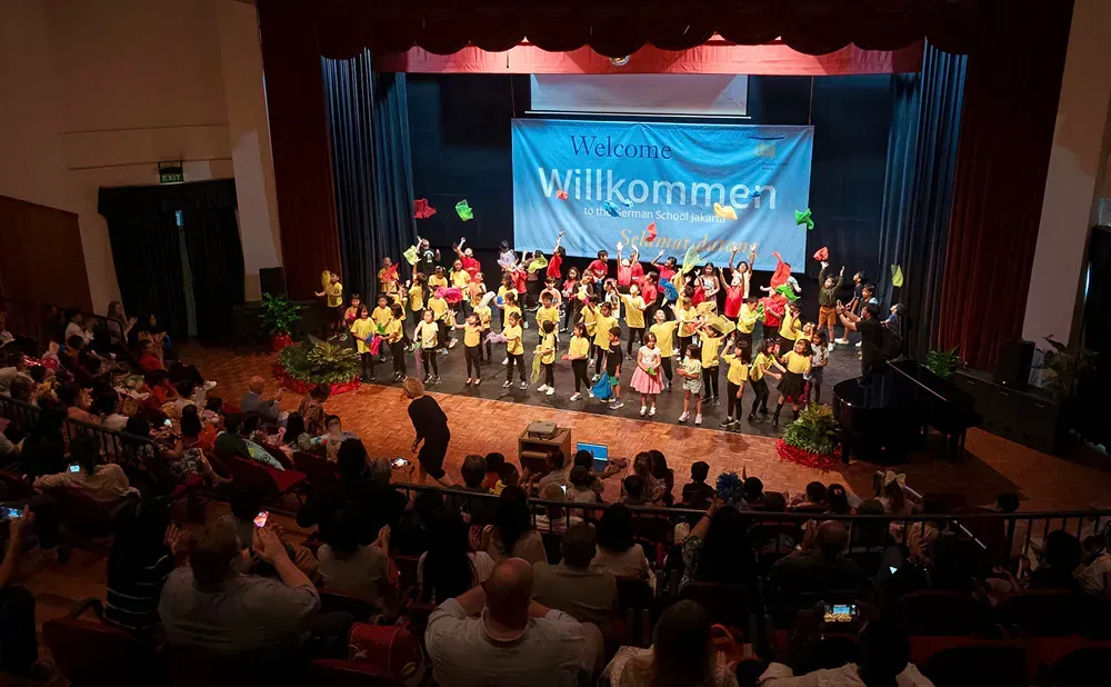 A large group of people are sitting in an auditorium watching a concert.