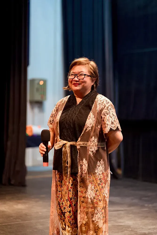 A woman is standing on a stage holding a microphone.