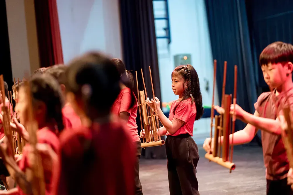 A group of children are playing wooden instruments on a stage.