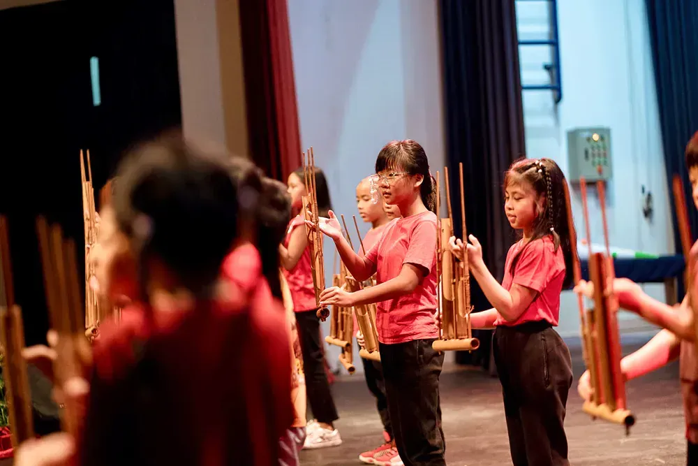 A group of children are playing wooden instruments on a stage.