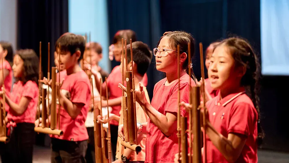 A group of children are playing traditional instruments on a stage.