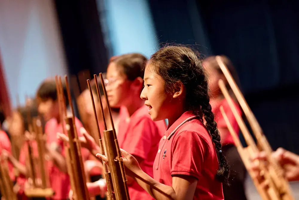 A group of children are playing instruments on a stage.
