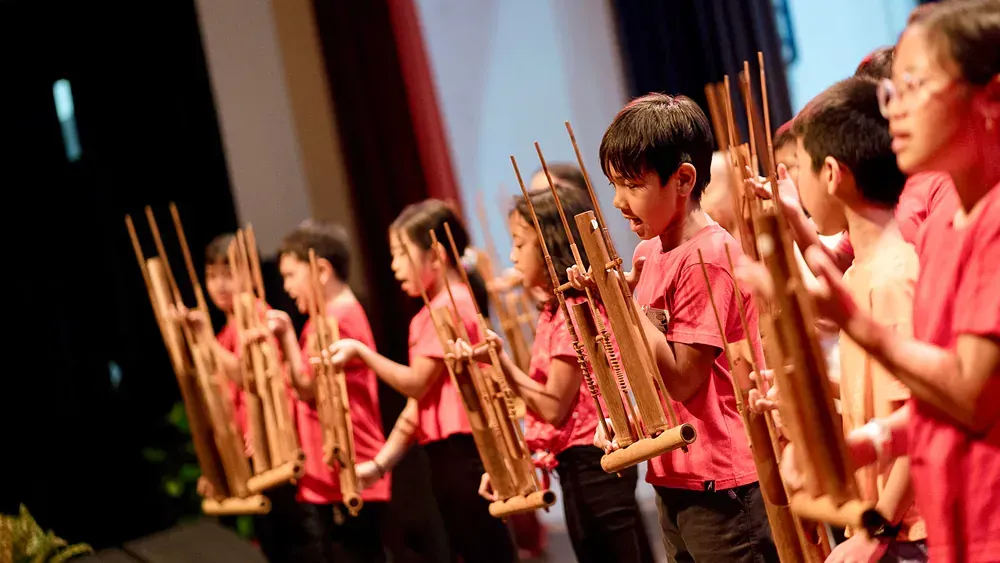 A group of children are playing wooden instruments on a stage.