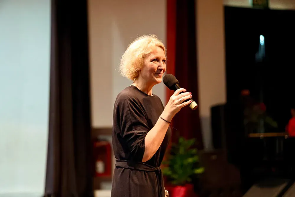 A woman is standing on a stage holding a microphone.