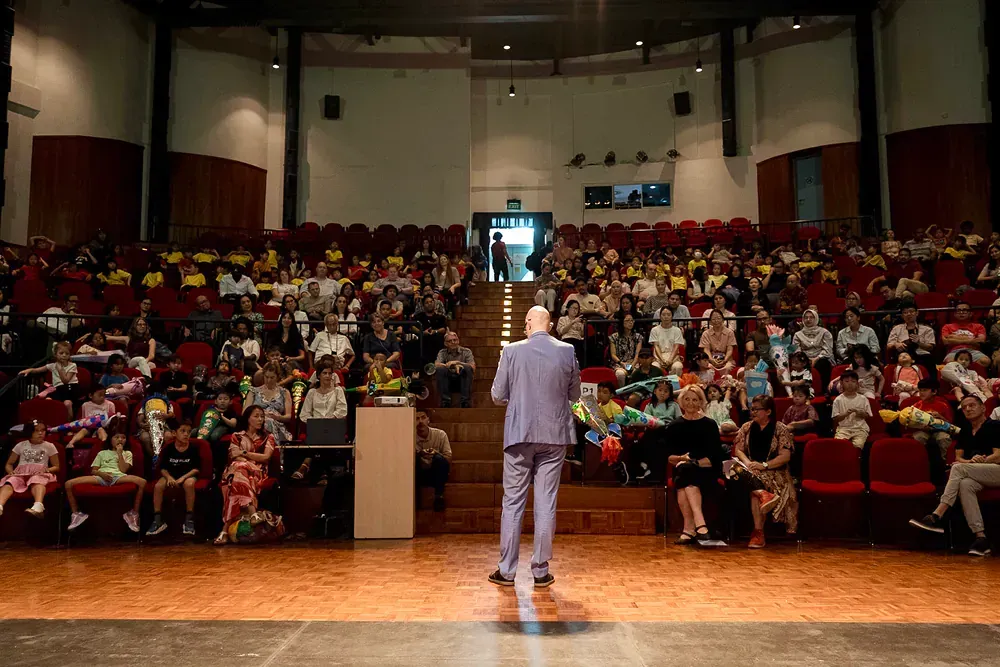A man in a suit is standing on a stage in front of a large audience.