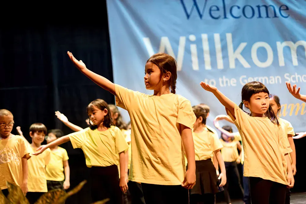 A group of children are dancing in front of a welcome sign