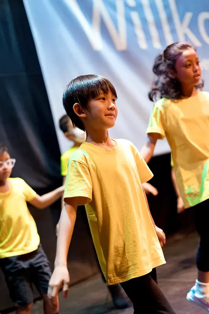 A group of young children are dancing on a stage.