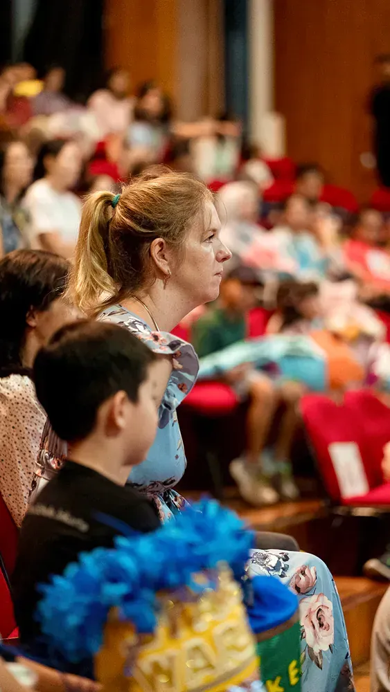 A woman is sitting in front of a crowd of people in a theater.