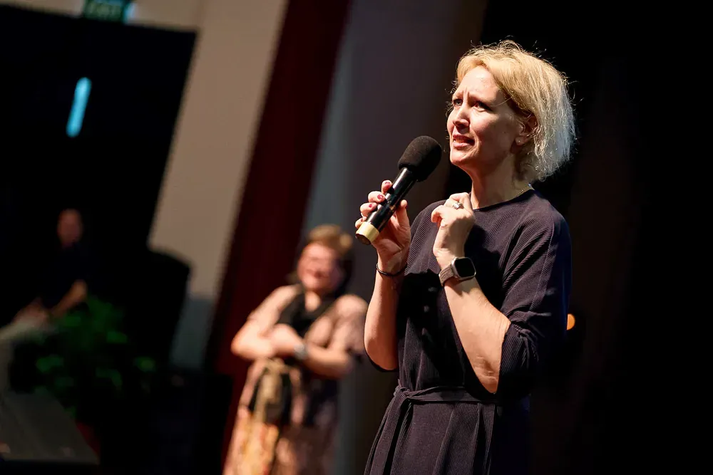 A woman is standing on a stage holding a microphone.