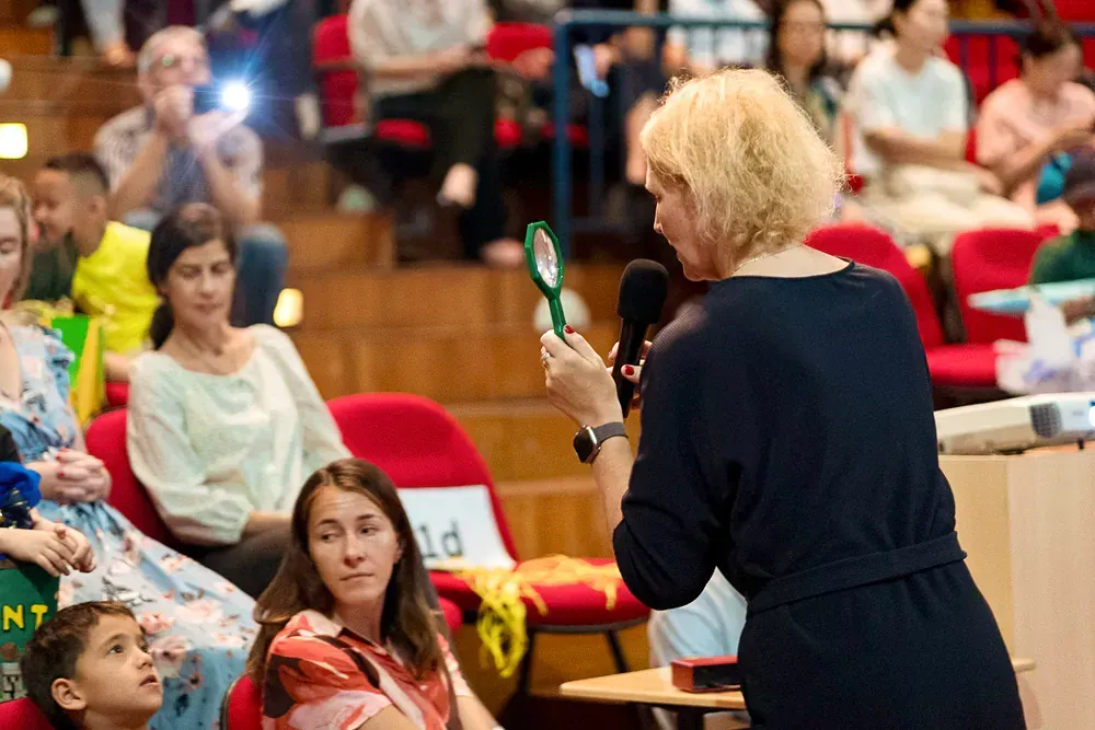 A woman is holding a microphone in front of a crowd of people.