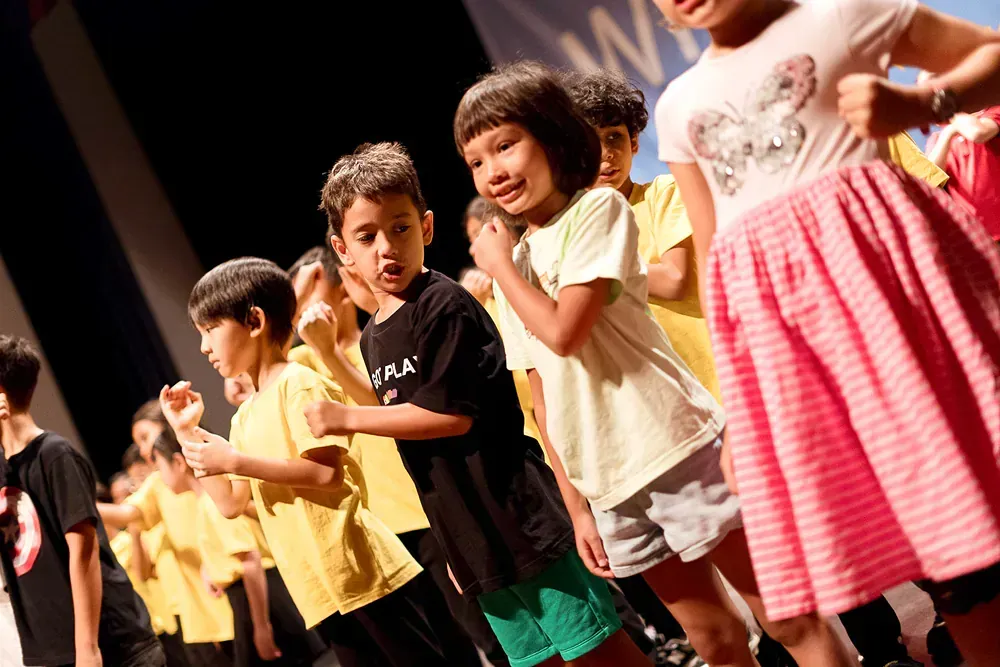 A group of children are standing in a line on a stage.