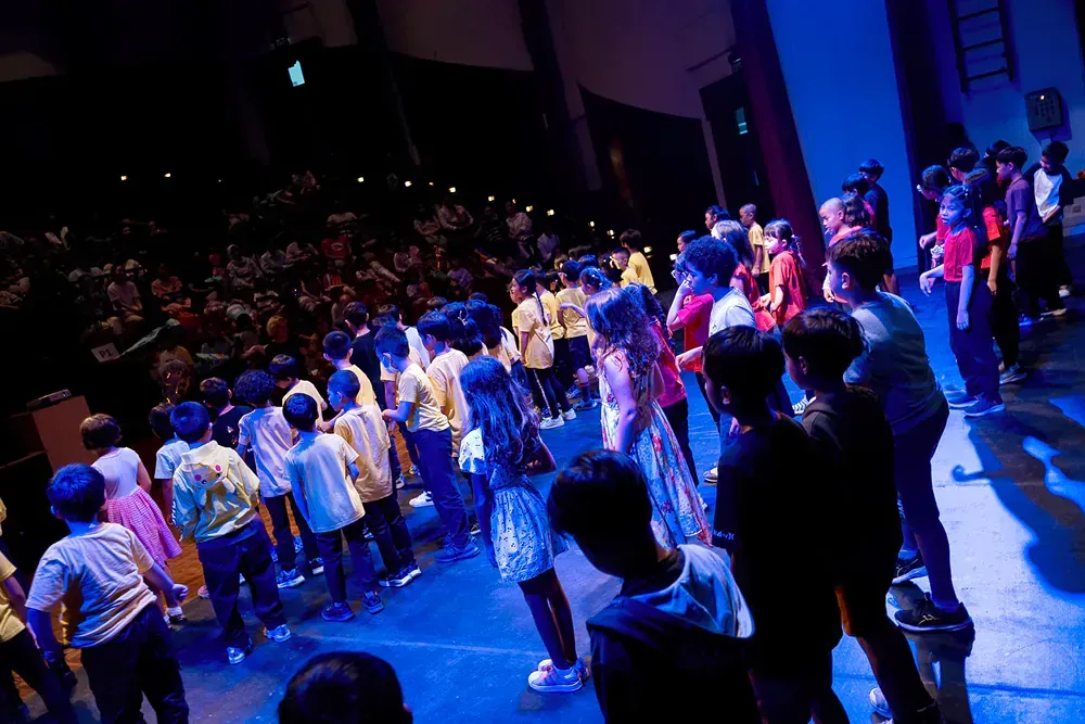 A group of children are standing on a stage in front of a crowd.