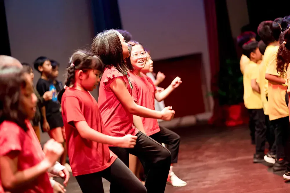 A group of children are dancing on a stage.