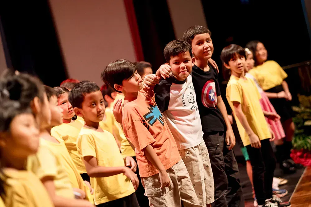 A group of children are standing next to each other on a stage.