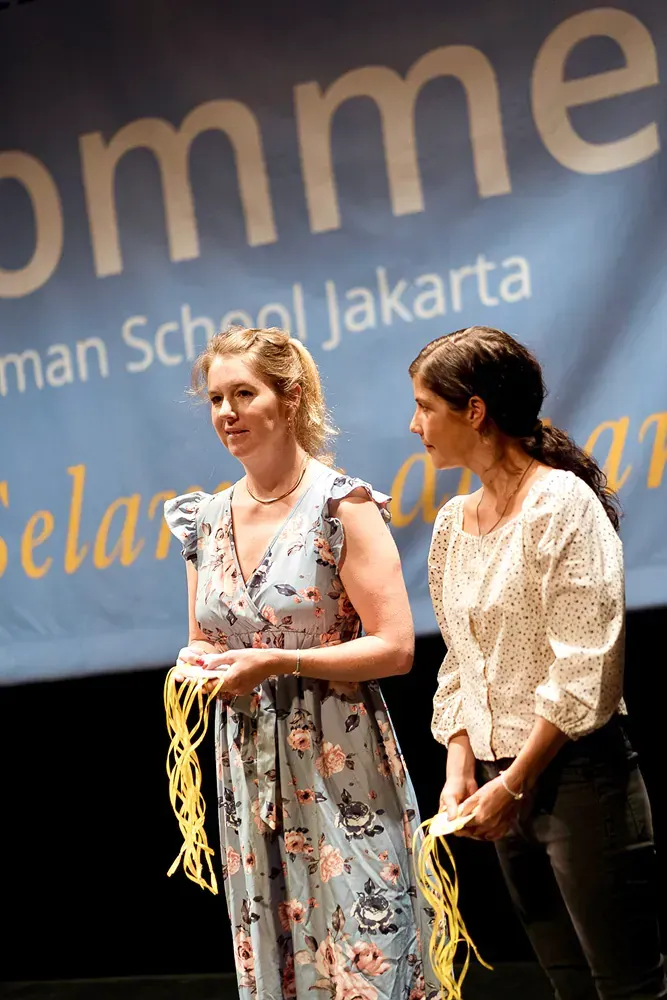 Two women standing in front of a banner that says omme