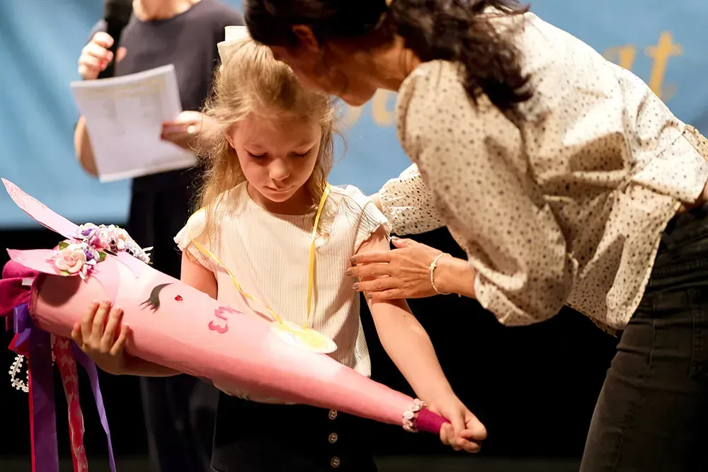A woman is helping a little girl with a pink cone.