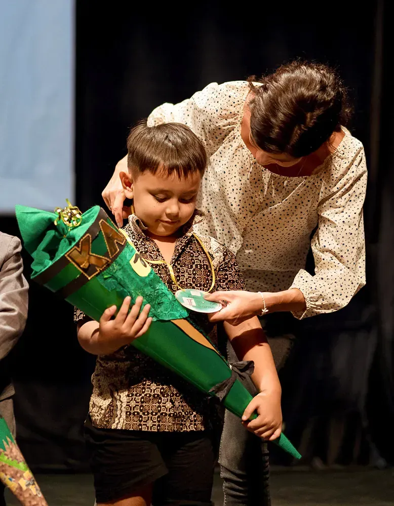 A woman is helping a young boy with a green cone.