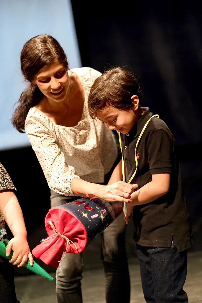 A woman is giving a child a cone with a name on it