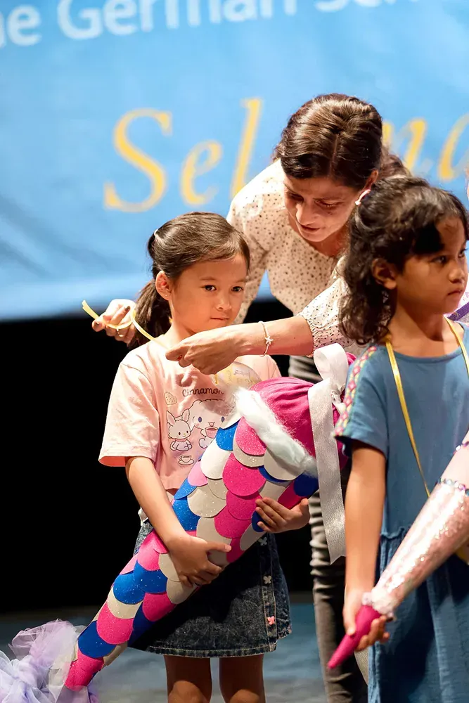 A woman is pointing at a girl holding a colorful cone.