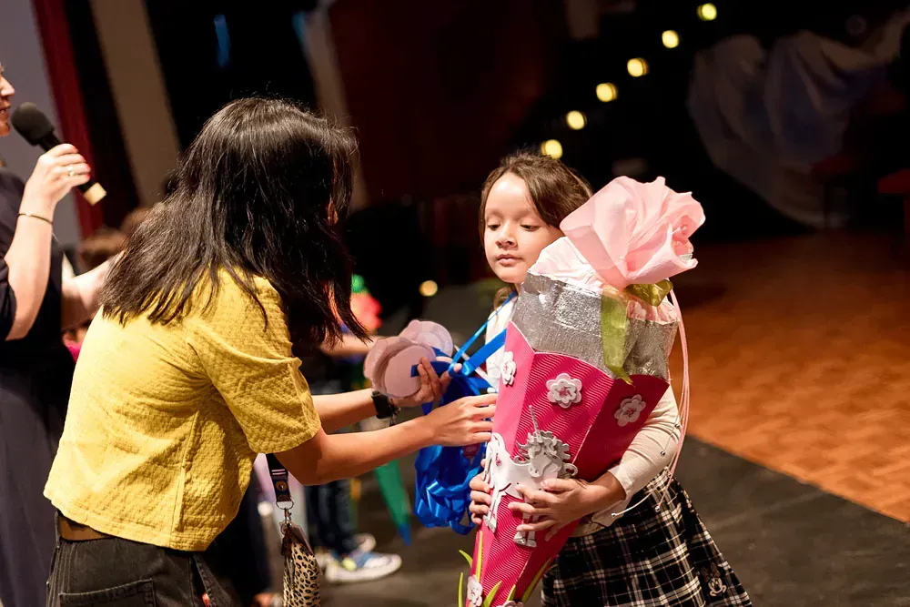 A woman is giving a little girl a bouquet of flowers.