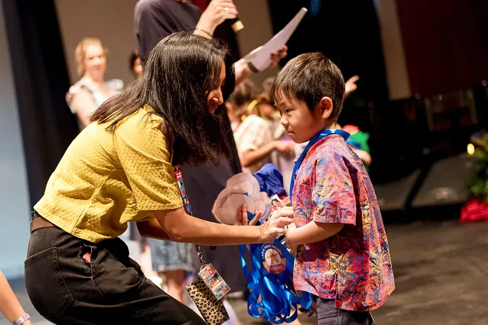 A woman is giving a medal to a young boy
