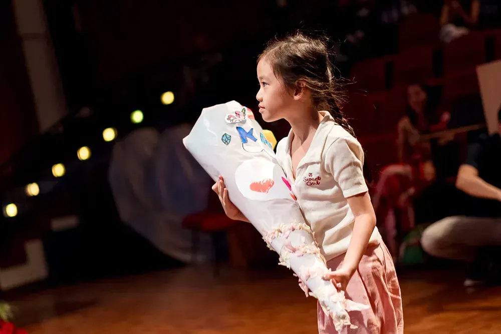 A little girl is holding a cone on a stage.