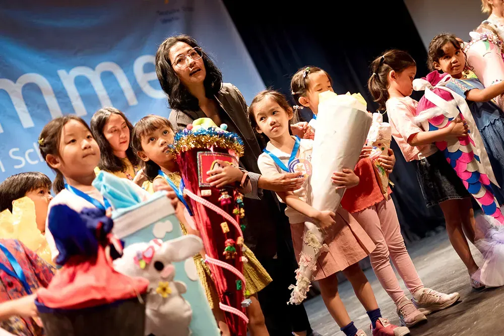 A group of young girls are standing on a stage holding flowers.