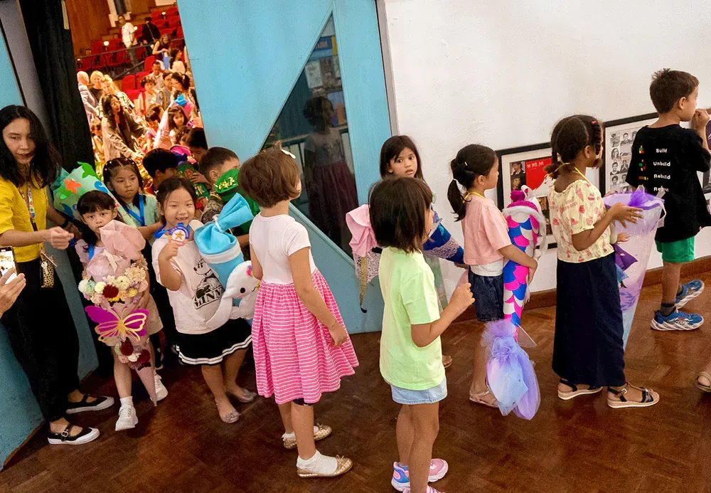 A group of children are standing in a room holding balloons.