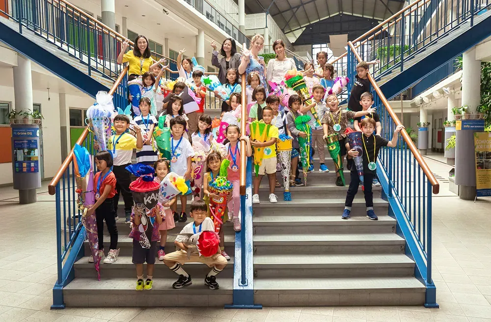 A group of children are posing for a picture on the stairs of a school.