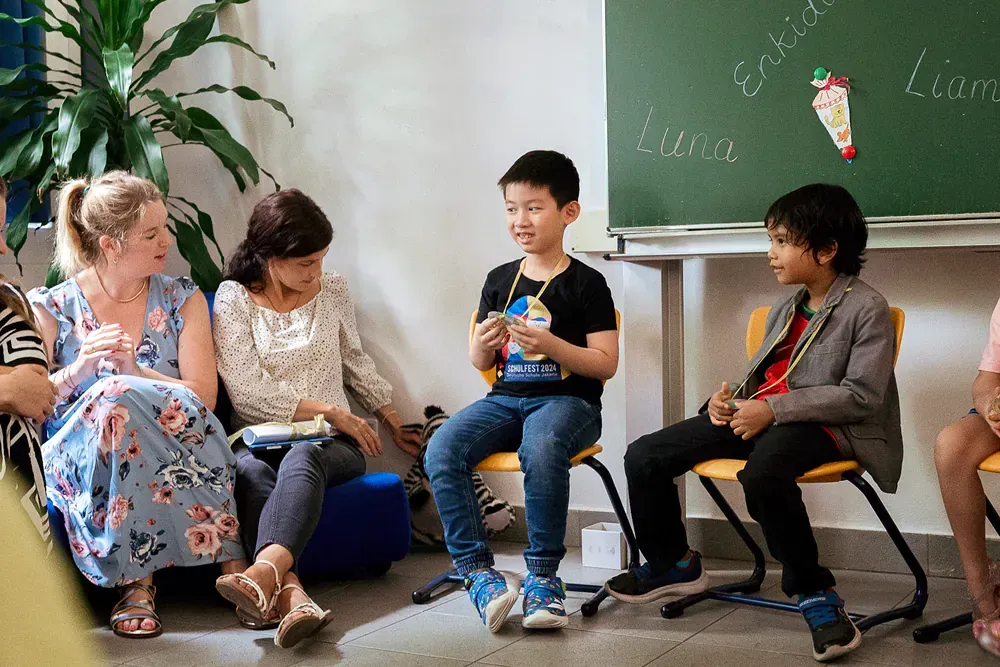 A group of children are sitting in a circle in front of a blackboard.