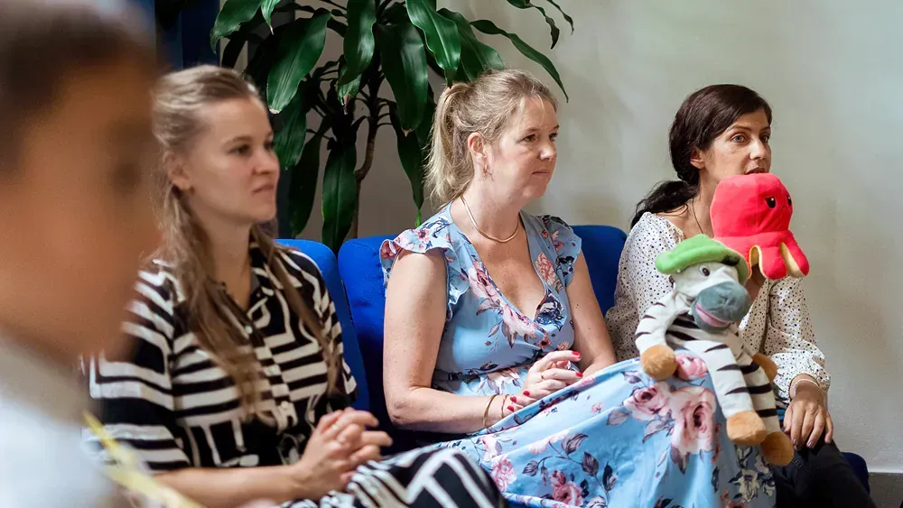 A group of women are sitting on a couch with stuffed animals.