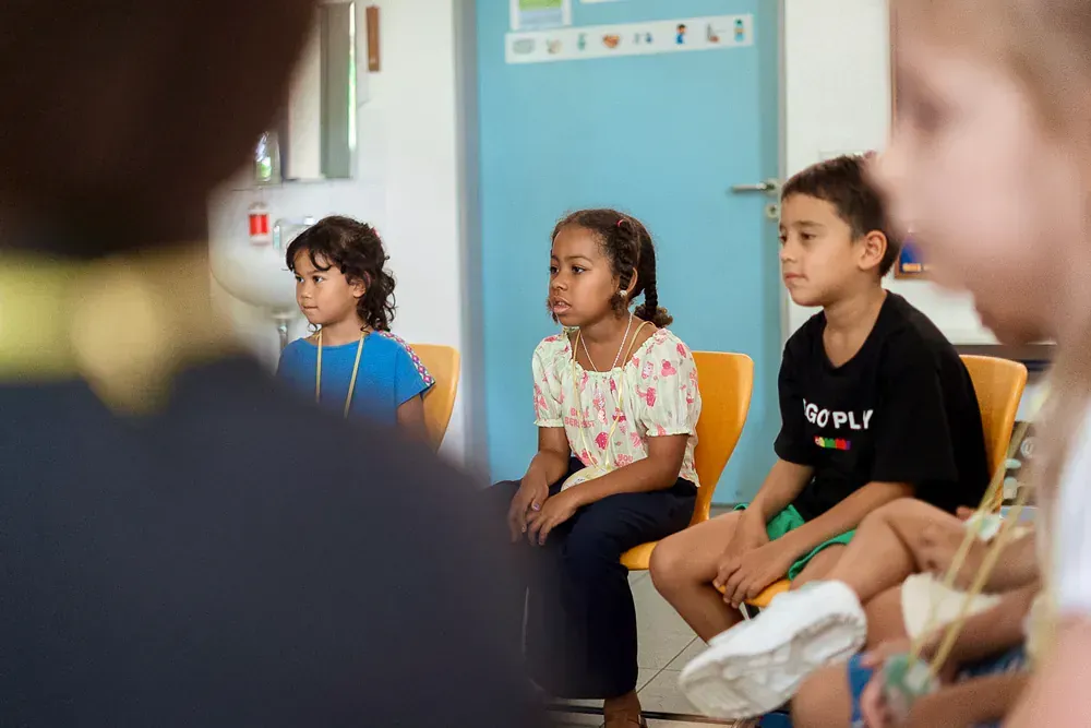 A group of children are sitting in a circle in a classroom.
