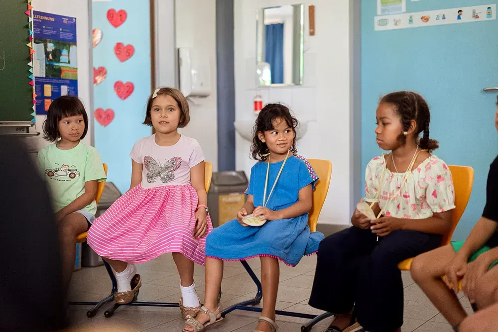 A group of young girls are sitting in a circle in a classroom.