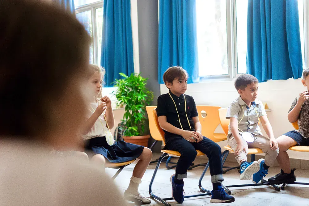 A group of children are sitting in a circle in a room.
