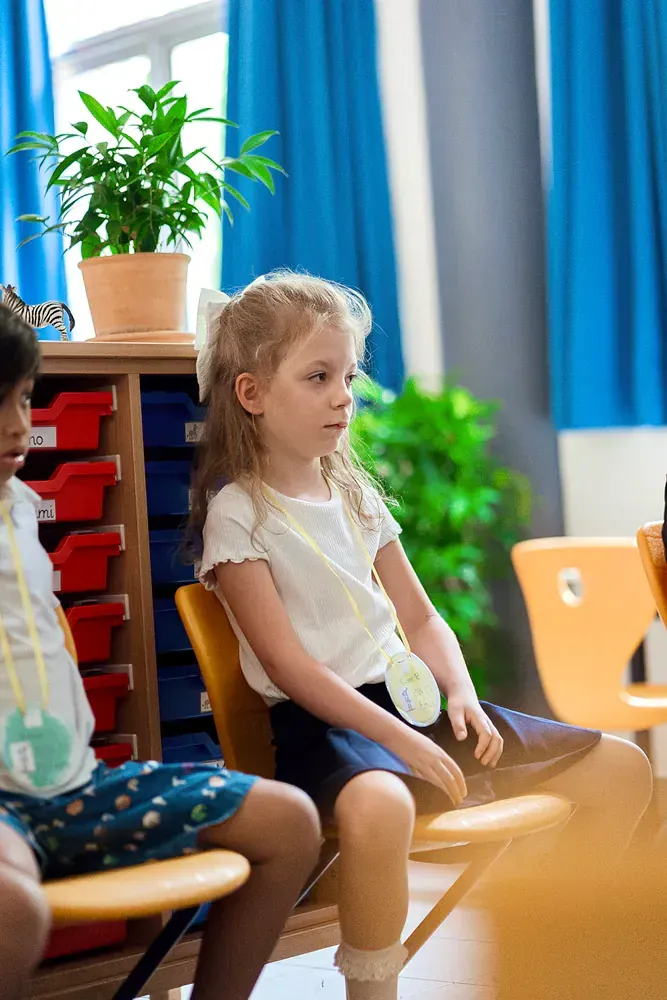 A group of children are sitting in chairs in a classroom.