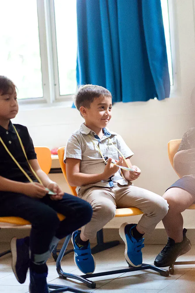 A group of children are sitting in chairs in a classroom.