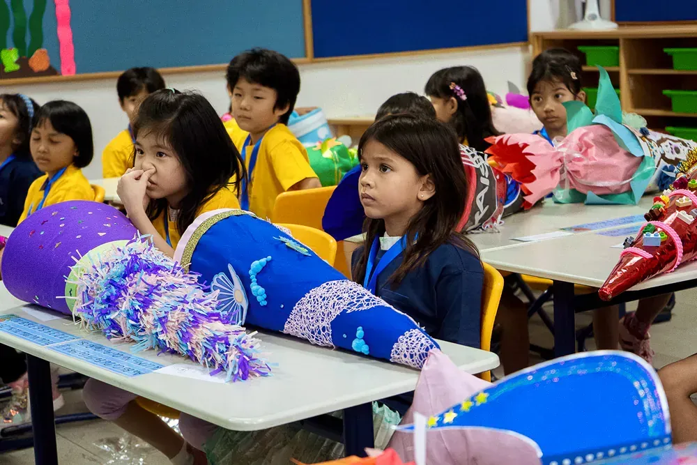 A group of children are sitting at their desks in a classroom.