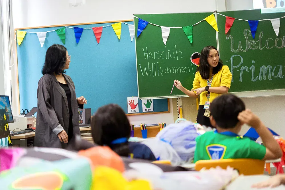 A teacher is standing in front of a classroom full of children.