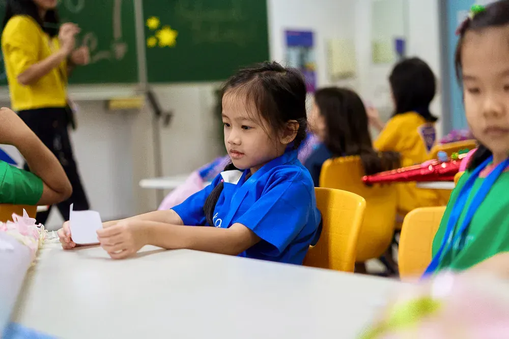A group of children are sitting at tables in a classroom.
