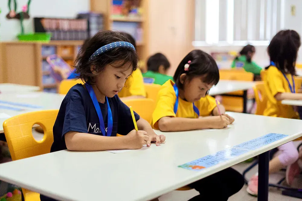 A group of young girls are sitting at desks in a classroom.