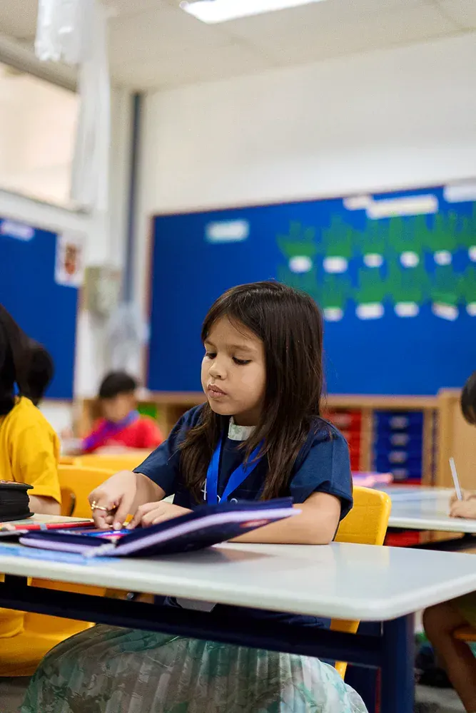 A young girl is sitting at a desk in a classroom.